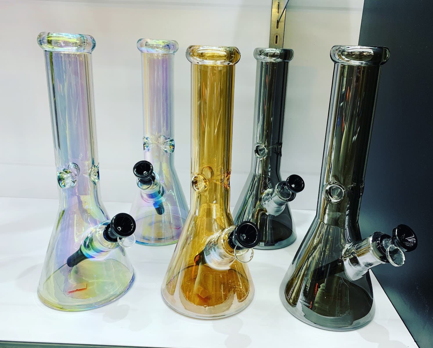 Beaker water pipes in iridescent, amber and smoke-grey glass at Six Fifty Smoke Shop.
