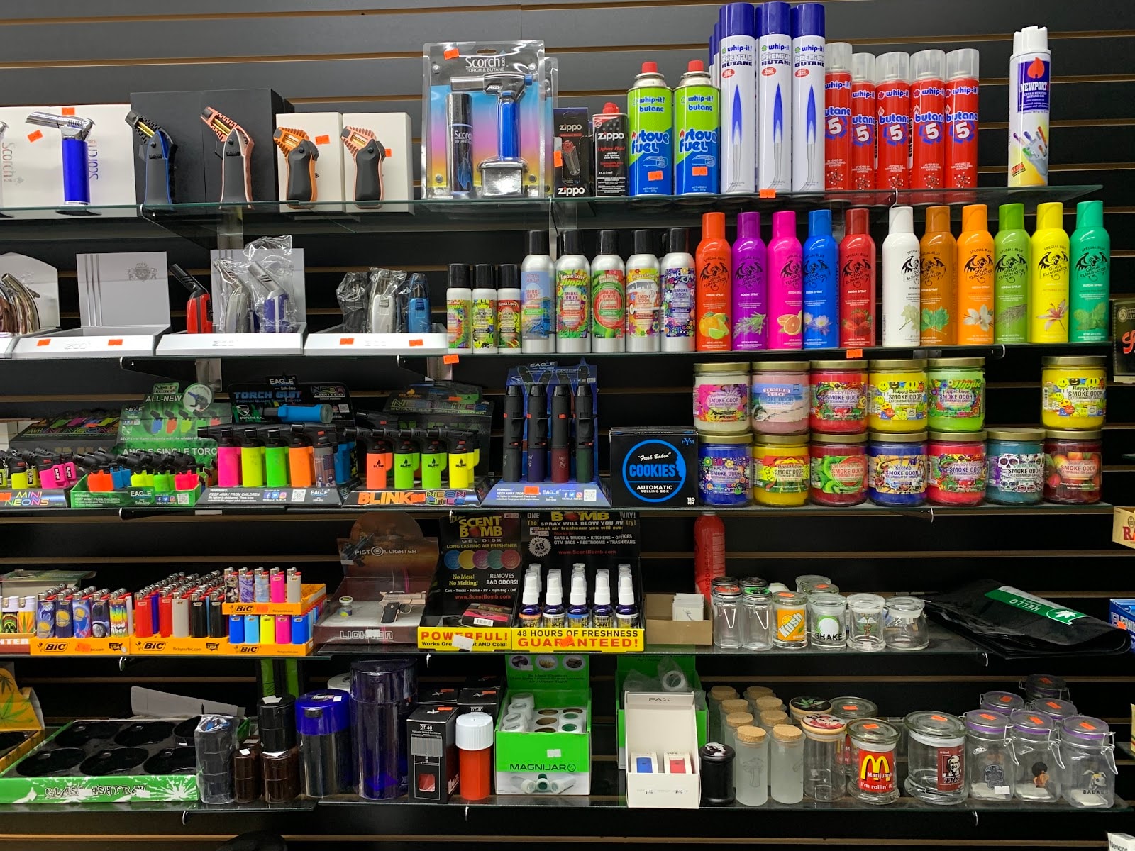 The accessory wall behind the counter at Six Fifty Smoke Shop, stacked with torches, butane, jars and grinders.