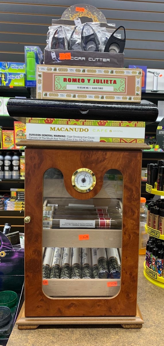 The cigar humidor at Six Fifty Smoke Shop, stocked with Romeo y Julieta and Macanudo alongside cutters and lighters.